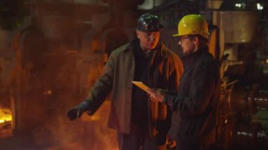 Mühendis ve işçi döküm içinde görüşme. Tablet kullanarak mühendis. Zorlu endüstriyel ortamlar.