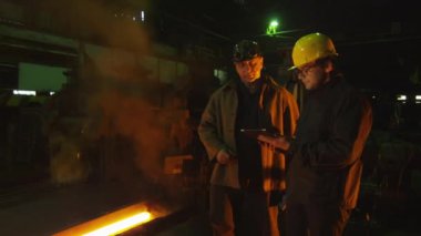 Mühendis ve işçi döküm içinde görüşme. Tablet kullanarak mühendis. Zorlu endüstriyel ortamlar.