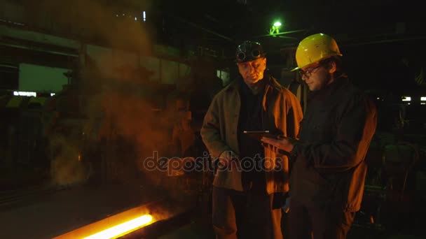 Ingénieur et travailleur ont une conversation à la fonderie. Ingénieur utilisant la tablette. Environnement industriel rude . — Video