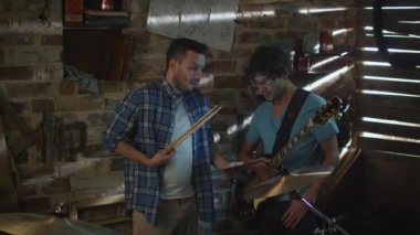 Bir garaj stüdyoda bir tablet bilgisayar kullanırken bir tartışma grubu müzisyenler var.