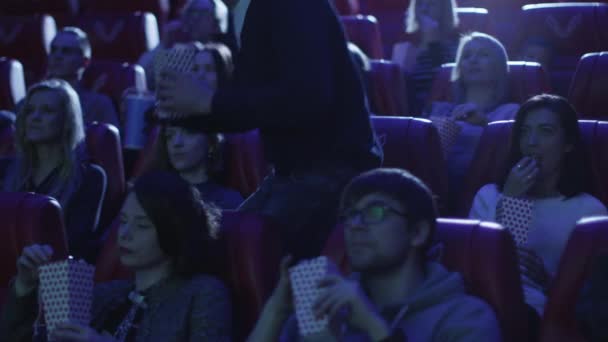 Man neemt zijn zetel terwijl mensen kijken een vlies zeef in een bioscoop cinema. — Stockvideo