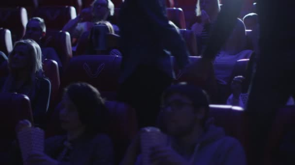 Pareja está tomando sus asientos mientras la gente está viendo una proyección de cine en un cine . — Vídeos de Stock