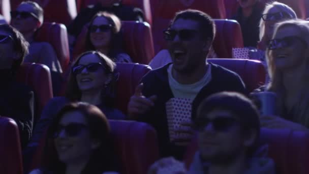 Gruppo di persone in occhiali 3d stanno ridendo mentre guardano una proiezione di un film commedia in un cinema . — Video Stock