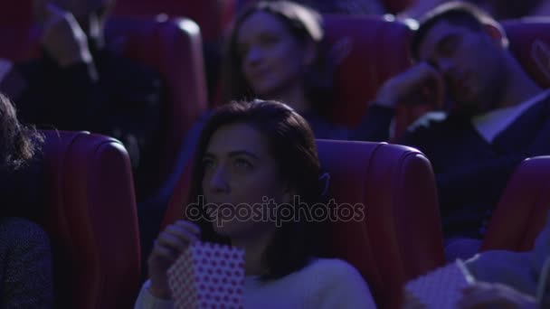 El hombre está durmiendo mientras la gente está viendo una proyección de cine en un cine . — Vídeo de stock