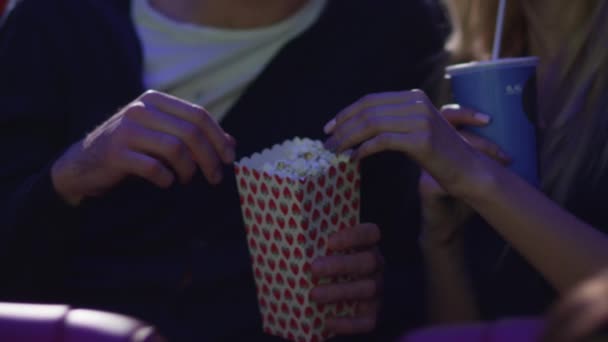 Joven pareja romántica feliz está viendo una proyección de cine mientras se toma de la mano en un cine de cine . — Vídeos de Stock