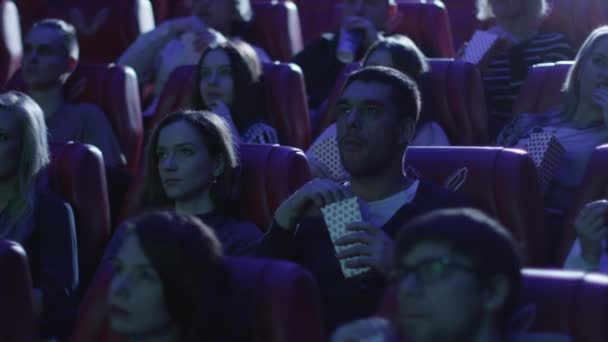 一群人都吓得一边看恐怖电影放映会在电影院看电影. — 图库视频影像