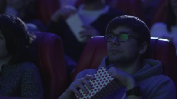 Grupa ludzi jedzą popcorn oglądając pokaz filmu w kinie cinema. — Wideo stockowe