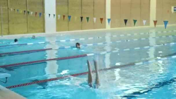 Profi-Schwimmerin springt aus dem Startblock und führt das vordere Krabbeln aus. Kamera folgt ihr. — Stockvideo