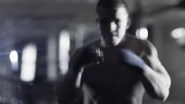 Professional male boxer is training punches and kicks in dark gym. — Stock Video