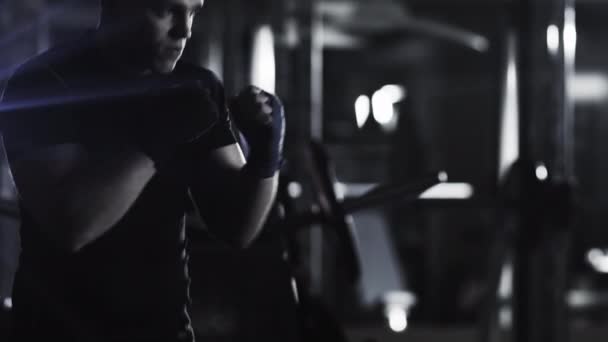 Boxeador masculino profissional está treinando socos e chutes no ginásio escuro . — Vídeo de Stock