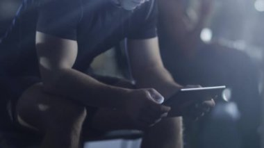 Uygun sportif yakışıklı spor salonunda bir tablet bilgisayar kullanıyor.