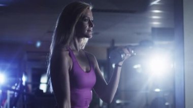 Çekici uygun sportif kız koyu spor salonunda dumbbells ile egzersiz.