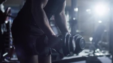 Halter curl egzersizleri koyu spor salonunda yakışıklı uygun sportif erkek yapar.