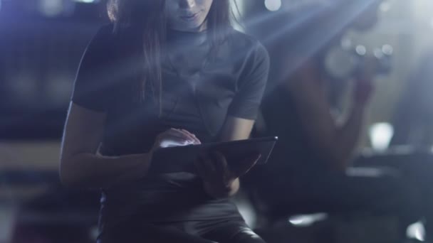 Ελκυστική γυναίκα ταιριάζει σπορ χρησιμοποιεί έναν υπολογιστή tablet στο γυμναστήριο. — Αρχείο Βίντεο