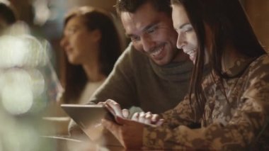 Erkek ve kadın kahkaha süre tablet kullanma ve bir barda iyi vakit geçiriyor.