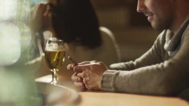 Bir bardak bira tezgaha ayakta iken adam bir ileti bir smartphone cep telefonu ile bir barda yazmakta olduğunu.