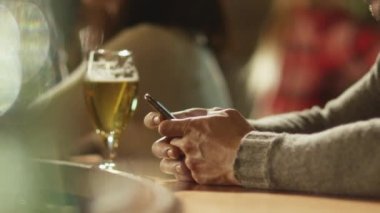 Bir bardak bira tezgaha ayakta iken adam bir ileti bir smartphone cep telefonu ile bir barda yazmakta olduğunu.