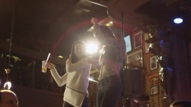 Herkes yaşıyorsanız iken iyi bir zaman birlikte bir barda iki kız içecekler ile bir tablo üzerinde dans ediyor.