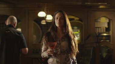 Mutlu çekici kız onun koltuk kalabalık bir barda bir içki ile yürüyor.