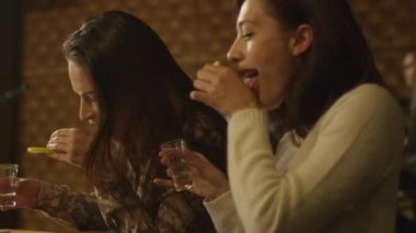 İki kız bir masada oturan ve iyi bir zaman birlikte bir çubuk yaparken tekila içmek.