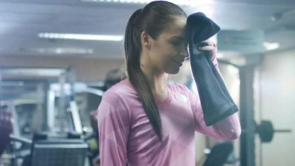 Приваблива спортсменка стирає обличчя рушником і позує в спортзалі . — стокове відео