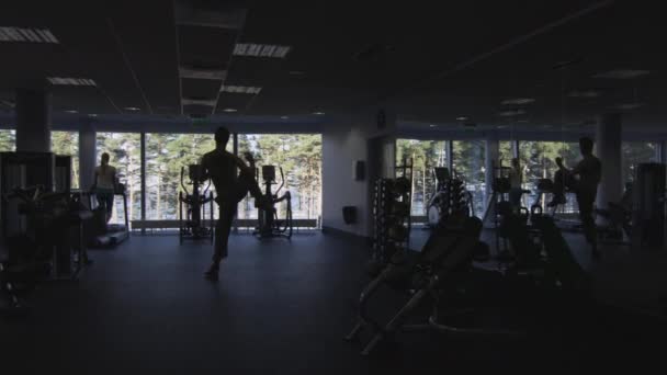 Filmación de la silueta de la gente haciendo ejercicio y entrenando en el gimnasio . — Vídeo de stock