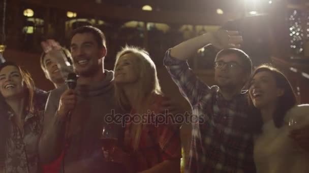 Los amigos están cantando canciones de karaoke mientras se divierten juntos en un bar . — Vídeos de Stock