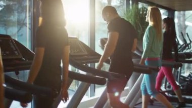 Genç atletik erkek süre egzersiz ve spor salonunda koşu bandı üzerinde çalışan akıllı telefon kullanıyor.