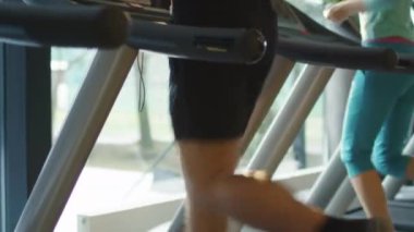 Egzersiz ve spor salonunda koşu bandı üzerinde çalışan kadın ve genç atletik erkek.