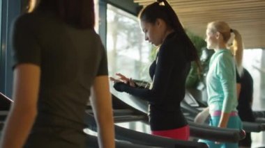 Kulaklık ile spor salonunda treadmill çalıştıran çekici beyaz kız.