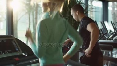 Egzersiz ve spor salonunda koşu bandı üzerinde çalışan kadın ve genç atletik erkek.