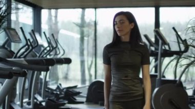 Atletik beyaz kız koşu bandı ile spor salonunda yürüyüş ve bir havlu kullanarak.