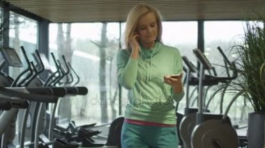 Çekici beyaz kız kulaklık ile spor salonunda treadmill üzerinde çalıştırmak başlıyor.