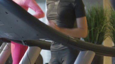 Ağır çekim görüntüleri egzersiz ve spor salonunda koşu bandı üzerinde çalışan kadın ve genç atletik erkek.