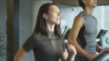 Ağır çekim görüntüleri egzersiz ve spor salonunda koşu bandı üzerinde çalışan kadın ve genç atletik erkek.