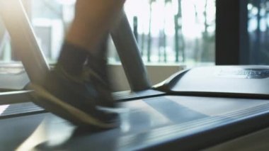 Egzersiz ve spor salonunda koşu bandı üzerinde çalışan sırasında adamın bacakları yakın çekim görüntüleri.