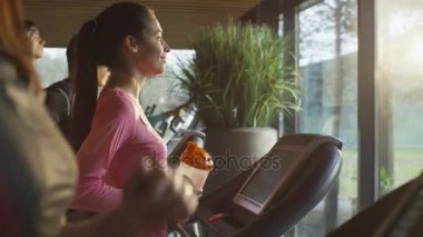 Uygun atletik kız spor salonunda treadmill egzersiz sırasında protein içeceği içiyor.