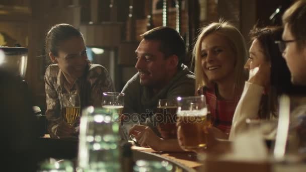 Друзья делают тосты, пьют пиво и коктейли, веселясь вместе в баре . — стоковое видео