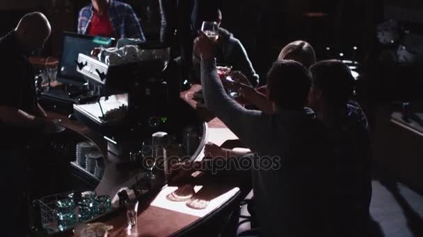 Δύο κορίτσια χορεύουν με ποτό σε τραπέζι ενώ όλοι έχουν μια καλή στιγμή μαζί σε ένα μπαρ. — Αρχείο Βίντεο