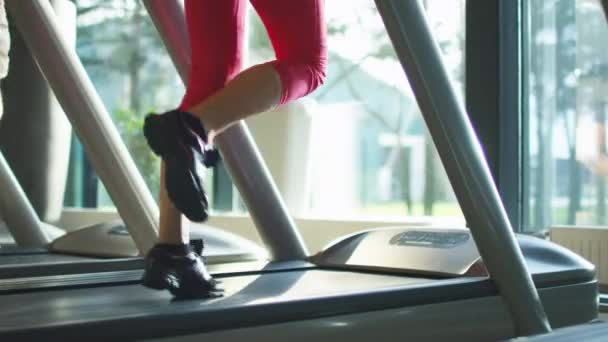 Съемки крупным планом мужских и женских ног, бегающих на беговой дорожке в спортзале . — стоковое видео