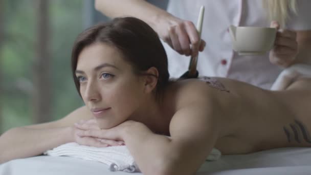 Jovem mulher bonita está recebendo um relaxante tratamento de massagem de chocolate no centro de bem-estar . — Vídeo de Stock