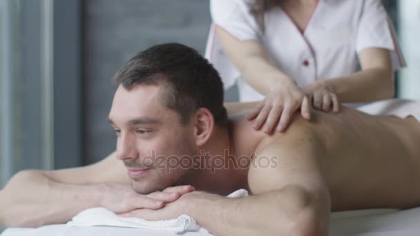 Bellissimo uomo sta ottenendo un massaggio rilassante da un massaggiatore donna nel centro benessere . — Video Stock