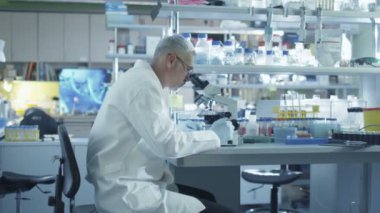 Erkek bilim adamı bir laboratuvar mikroskop üzerinde çalışıyor.