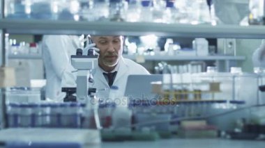 Üst düzey erkek bilim adamı bir laboratuvarda bir telefonda konuşuyor.