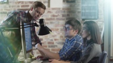 Genç yaratıcı Kişilik ekibin bir bilgisayar ekranında bir çalışma projesi görüşüyorlar.