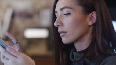 Genç kadın tasarımcı kullanıcı arabiriminde bir akıllı telefon ve bilgisayar test ediyor.