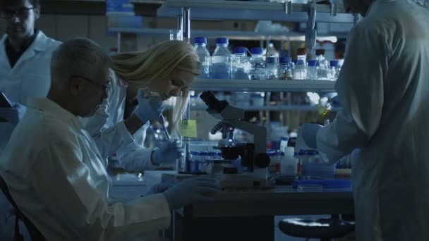 Grupo de científicos caucásicos en batas blancas están trabajando en un moderno laboratorio por la noche . — Vídeo de stock
