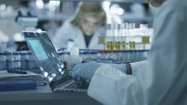 Gruppe kaukasischer Wissenschaftler in weißen Kitteln arbeiten in einem modernen Labor. — Stockvideo
