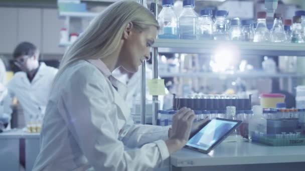 Женщина-ученый использует планшет во время работы в лаборатории . — стоковое видео