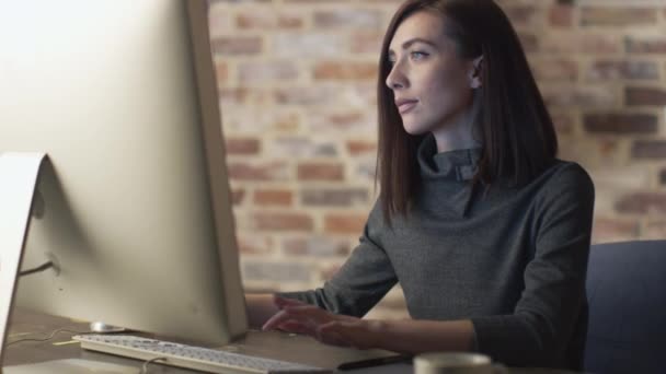 Mladá bruneta žena pracuje v přední části monitoru v podkroví. — Stock video